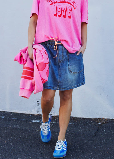 Hammill & Co New stretch denim skirt in slightly distressed stonewash denim. Elastic waist, orange multi draw cord, front scoop pockets, back patch pockets with our red heart embroidery on the back left pocket.