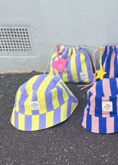 Hammill & Co bold striped bucket hat is pure summer happiness. Made from soft terry towelling in vibrant mauve/lemon stripes, it adds a playful pop to any outfit. 