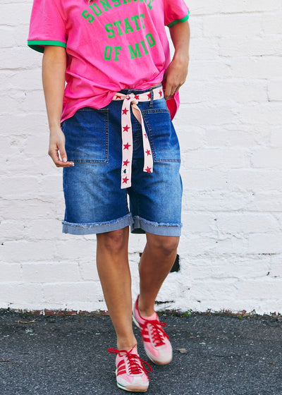 Hammill & Co A pair of longer-length darker denim stretch shorts with a relaxed fit. They have front pockets, a raw rolled hem, and sit mid-thigh. 