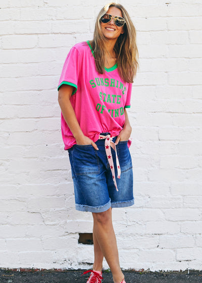 Hammill & Co A pair of longer-length darker denim stretch shorts with a relaxed fit. They have front pockets, a raw rolled hem, and sit mid-thigh. 